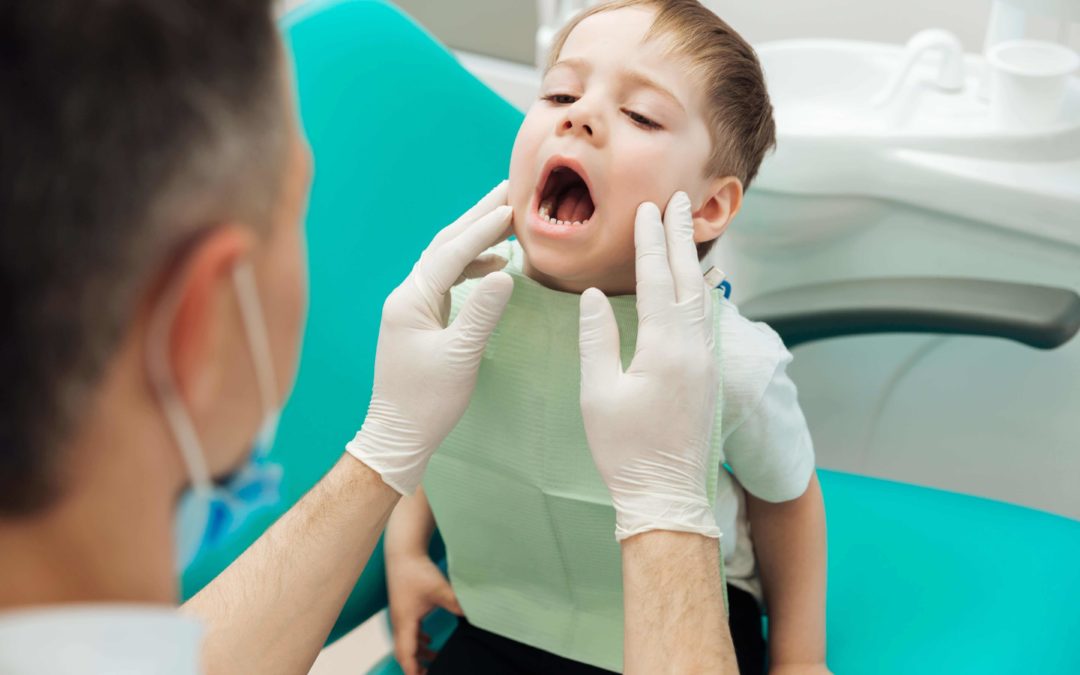dentist examining the mouth of a young boy child