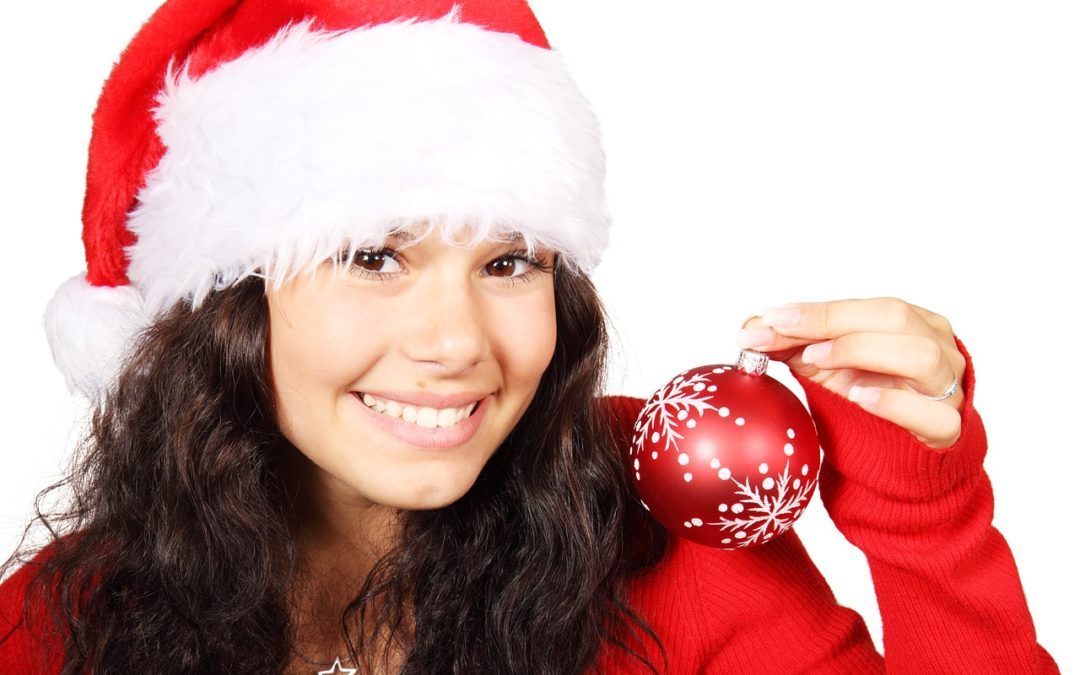 woman wearing santa hat holding a holiday ornament