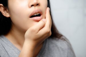 woman holding her jaw because her mouth is in pain