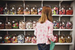 child looking at a wall of candy in a candy shop