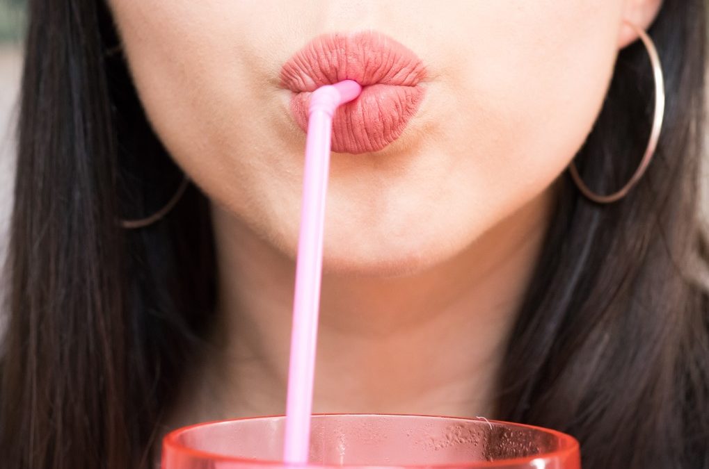 close up of a woman drinking through a straw
