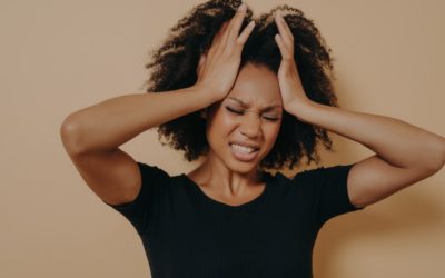 black woman with hands on her head and teeth clinched showing she's stressed