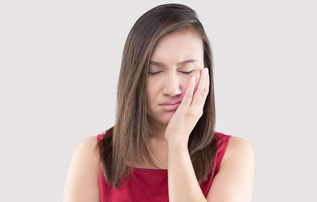 woman holding her jaw because she's suffering from jaw pain