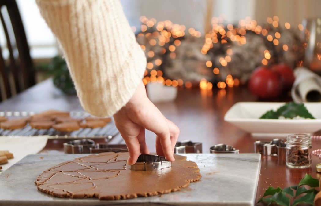 person cutting out gingerbread cookies for the holidays